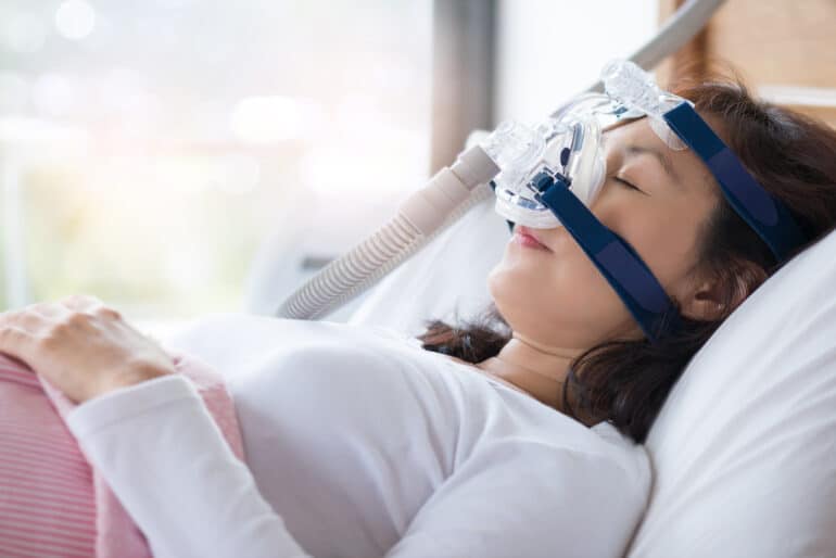 Woman sleeping soundly with CPAP machine.