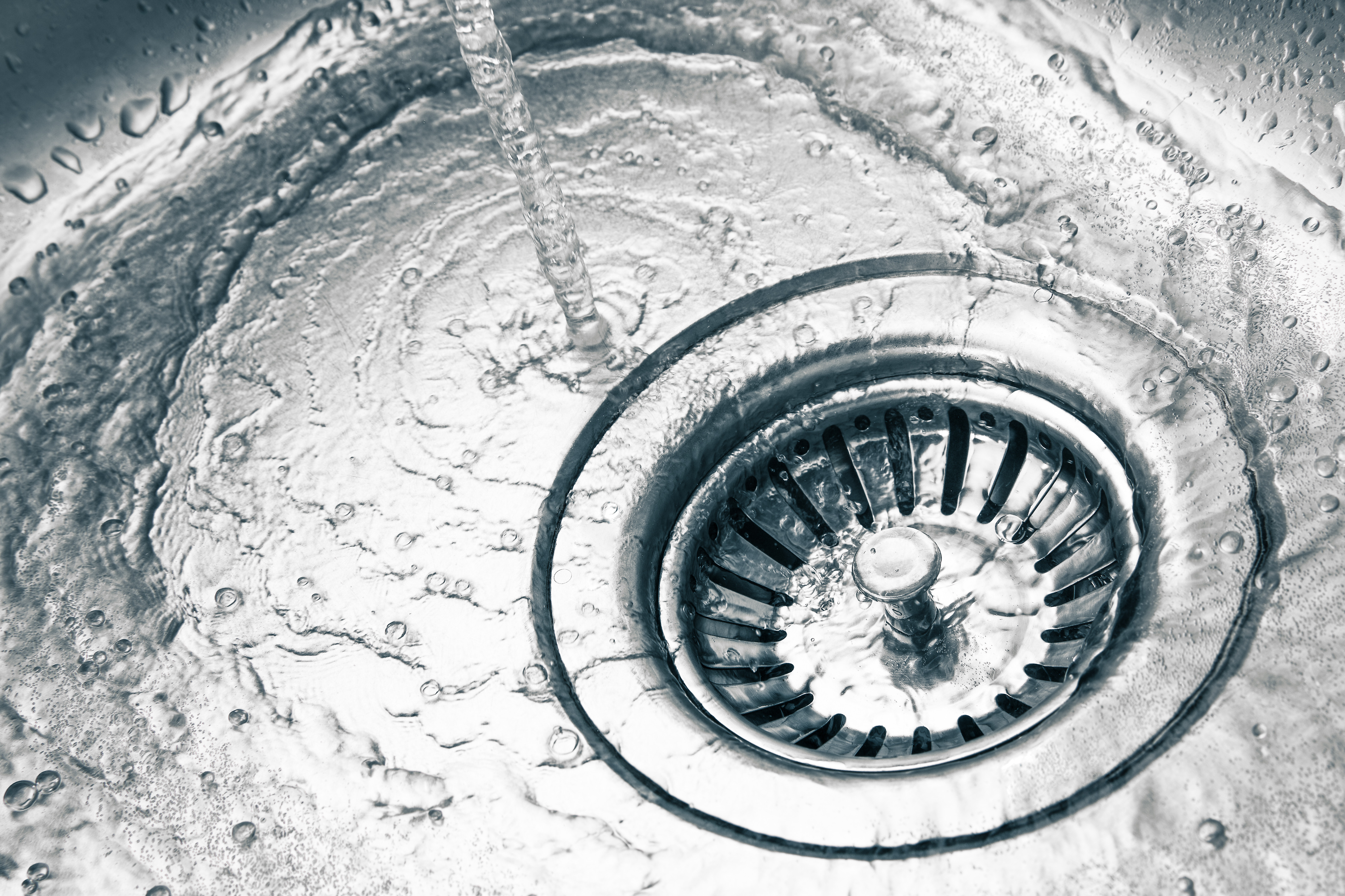 closeup of a kitchen sink drain with water running