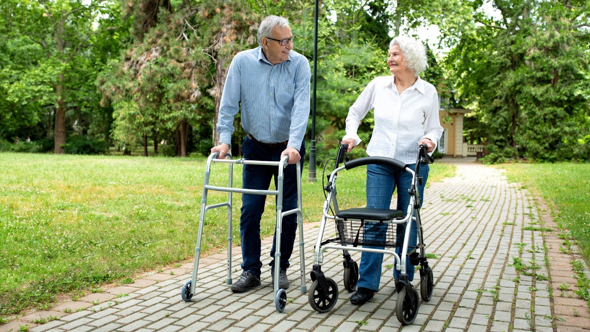 senior couple strolling outside with mobility walkers