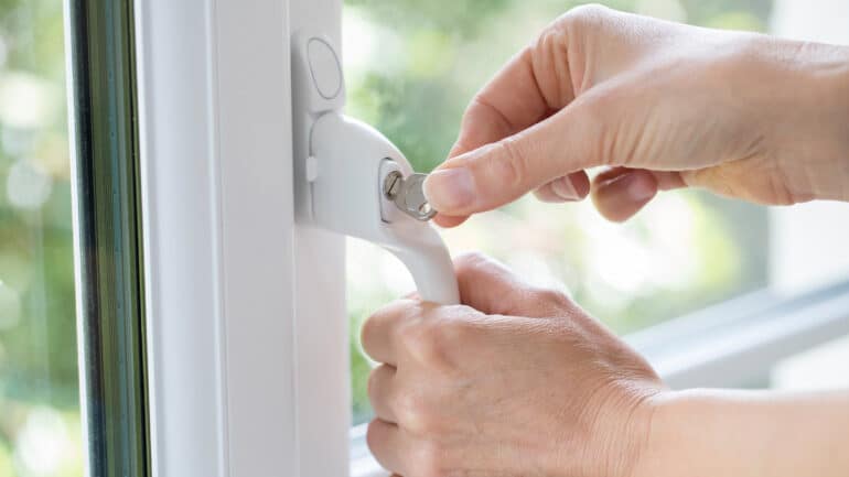 Closeup of woman turning key in window lock
